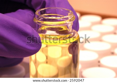 close-up of a hand with a small bottle in a research lab