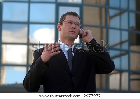 Business call.Young businessman talking to the cell phone in front of an office  .