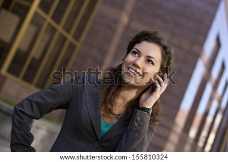 Young business woman talking on phone near the business center building. Sure girl. Smiling girl. Girl in a business suit. A woman Manager. The business woman. Cute, beautiful. The world of business.