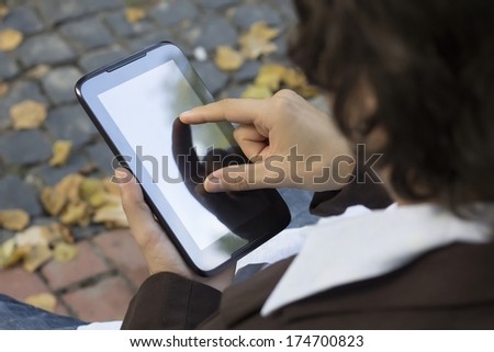 Young businessman using tablet pc in the autumn park. Start up. Busy businessman. Hand touching screen of tablet. Man using a tablet on the street. To work remotely as a freelancer.