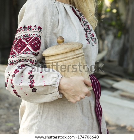 Woman in ethnic embroidery shirt holding wooden casket