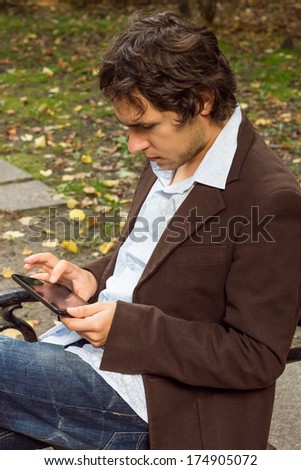 Man in brown suit working on tablet PC at the park