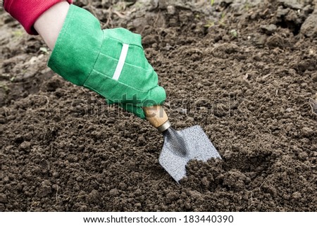 Arm in green glove with trowel which depicts the operation of the greenhouse