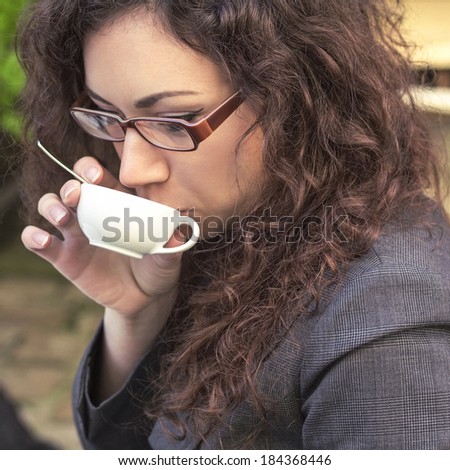 Girl with curly long hair in a business suit drinking coffee outdoor