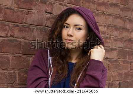 Young brown-eyed girl with curly hair and an easy smile, putting on hood
