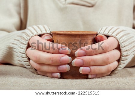 Women\'s hands with a long-sleeved sweater with a cup