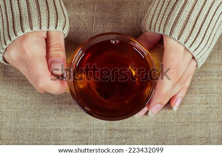Graceful hands of a girl with a cup of tea and a long-sleeved shirt, symbolizing the comfort of home