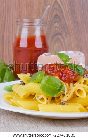 The composition of Italian pasta and jars of sauce on the table. Macaroni carnations fresh basil. Appetizing pasta