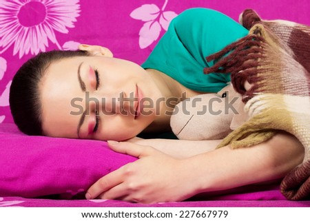Sweetly sleeping beautiful girl brunette, covered with warm blanket. Young woman sleeping with a toy. Healthy Sleep