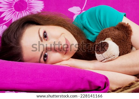 Woken up beautiful girl in bed with a soft toy. Smiling girl in the bed close-up. Brunette with brown eyes. Beauty portrait of young woman