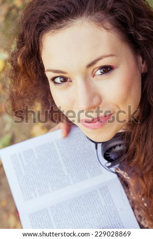 Beautiful girl in a park reading a book. Closeup portrait of beautiful smiling girl in autumn park. Student girl in the park