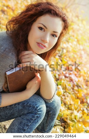 The girl with a book in the park. A student with a book in autumn park