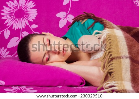 Young woman sleeping with a toy. Healthy Sleep. Sweetly sleeping beautiful girl brunette, covered with warm blanket.