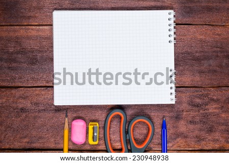Writing utensils on the table. Notebook, pen, pencil, scissors, eraser and sharpener stiraltelnaya on the table. Composition on the theme of education. Notebook close up on the table