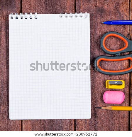 Composition on the theme of education. Notebook close up on the table. Writing utensils on the table. Notebook, pen, pencil, scissors, eraser and sharpener stiraltelnaya on the table.