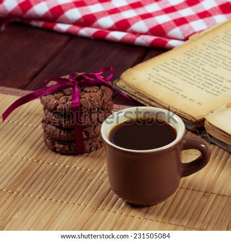 A cup of espresso on the table. Coffee and biscuits as breakfast. Spending time reading books. The book, coffee and biscuits on a wooden table.