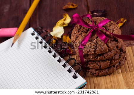 Notepad with stationery on wooden table. Chocolate cookies tied with a ribbon on the table. Vintage atmosphere. The idea of Ã¢??Ã¢??finding inspiration for starting a new business or writing works.
