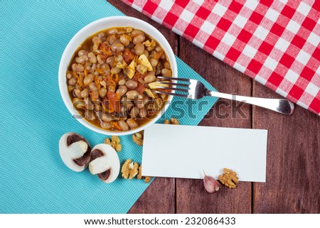 Hearty meal on the table. Lobio beans, carrots, onions, nuts and mushrooms in a bowl. Spicy dishes of Georgian and Armenian national cuisine. Vegetarian lunch. Empty blank for text near the bowl.