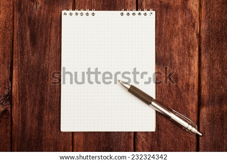 Open spiral notebook on a desk. Notebook and pen on the wooden table. Place for an inscription, the banner.
