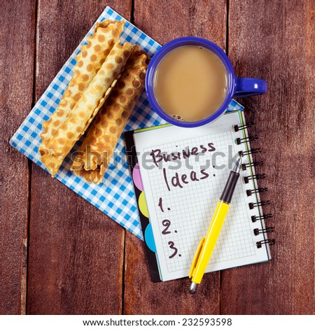 The idea of new beginnings in business start up. Waffles and coffee cup on the table next to the Notepad. Notepad to compile a list of business ideas.