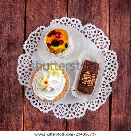 Three delicious cakes on a napkin on a wooden table. Cakes in the cafeteria. Sweet pastries for dessert