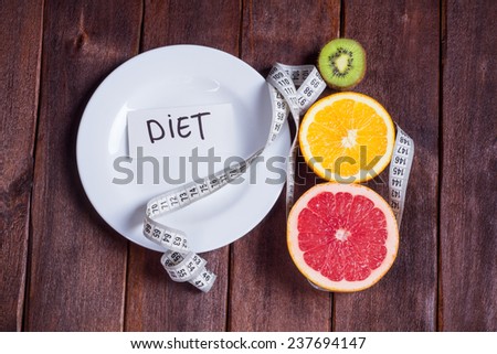 Concept of diet. Low-calorie fruit diet. Diet for weight loss. Plate with measuring tape and fruits on the table. Vegetarian diet for weight loss. Wellness.