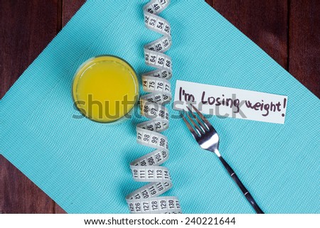 Glass of orange juice, fork, measuring tape and a note on the table. The idea of Ã?Â¢??Ã?Â¢??losing weight and a strict diet. Low-fat diet. The concept of loss of excess weight.