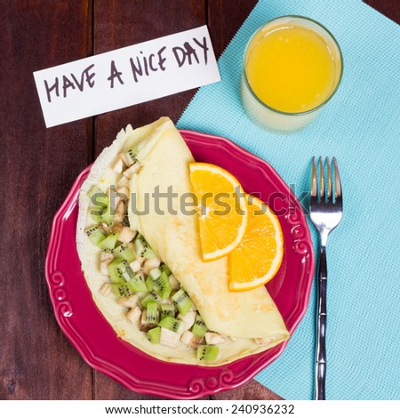 Cooked breakfast with love. Fruit pancake breakfast and a glass of orange juice. Fork, a plate of food, a note and a glass of juice on the table. Have a nice day.