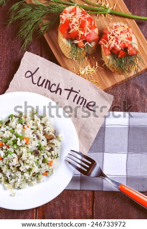 Traditions of Italian cuisine. Delicious lunch of bruschetta and risotto. Rice with vegetables on the table. Culinary traditions. Bruschetta on a board,  Risotto with mushrooms and vegetables.