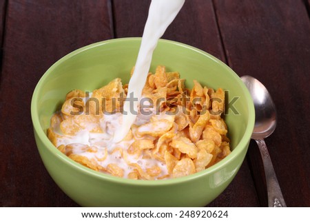 Easy breakfast of cornflakes and milk. Classic breakfast of cereal. The jet of milk and a bowl of cereal. Pour cereal with milk. Quick breakfast.