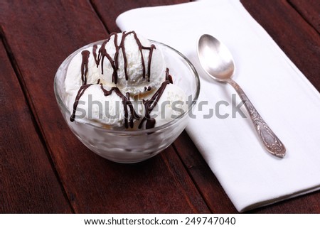Vanilla ice cream in a bowl with chocolate sauce. Ice cream and spoon on the table. Delicious dessert. Refreshing ice cream. In the cafeteria.
