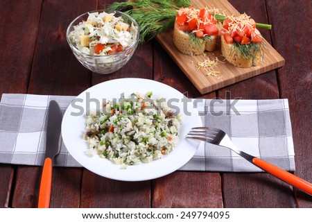 Rice with vegetables and bruschetta on the table. Salad, bruschetta with tomatoes and risotto on the table. A hearty lunch. Healthy food. Italian dishes.