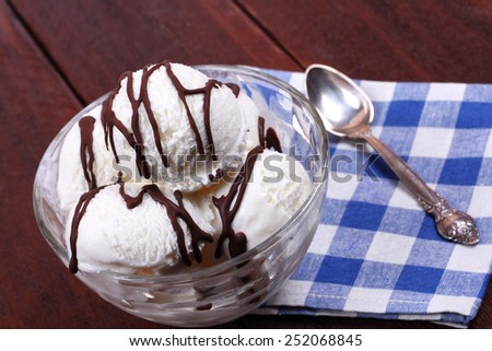 Vanilla ice cream with chocolate icing. Serving dishes in the cafeteria or restaurant. Bowls of ice cream, spoon and napkin. Ice cream on the kitchen table.