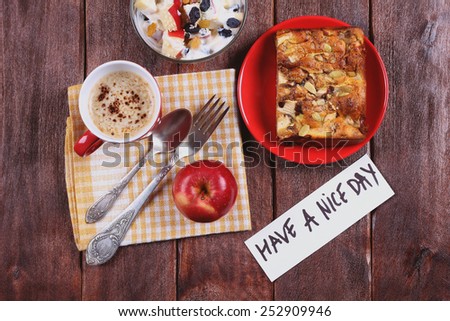 Fruit salad with yogurt, cutlery, apple pie and apple on the table. A delicious and hearty breakfast. Pastries and cappuccino. A cup of coffee on the table. Note the wish. Surprise for a loved one.