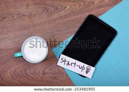 A cup of milk or yogurt on the table. Tablet PC on the desk. Tablet and a cup. The concept of start-up, a new business. Space for text, banner.