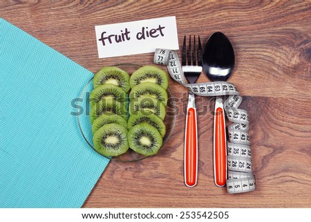 Sliced kiwi on a plate. Fork, spoon, plate. Concept of healthy food, fruit diet. Diet, healthy lifestyle. Measuring tape, fork and spoon. Space for text, banner.