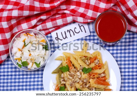 A plate of pasta with mushrooms and grated cheese. Italian pasta of different colors on a plate. Plate of pasta salad and a bowl of Chinese cabbage on the table. Delicious and hearty lunch. Top view.