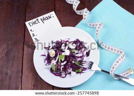 Vegetable salad for weight loss. The concept of diet and dietary food. Diet plan diet. Kitchen table, tape measure, a plate with salad, a fork and a banner with the text. Healthy food.