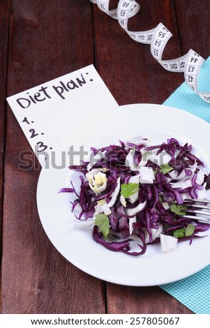 The concept of diet and dietary food. Diet plan diet. Vegetable salad for weight loss. Kitchen table, tape measure, a plate with salad, a fork and a banner with the text. Healthy food.