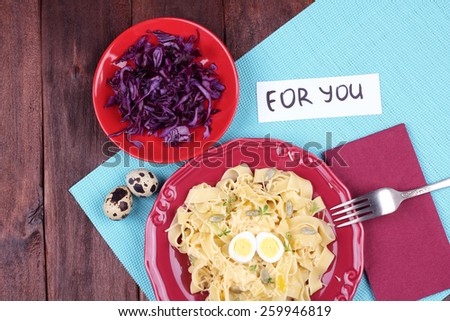 Egg pasta with quail egg, watercress salad and seeds. Dish pasta and coleslaw on the table. Delicious hearty lunch. Surprise for dear person. Top view. Pasta dish.