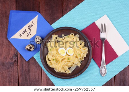 Fork and plate. Plate with egg pasta on the table. Love letter on the table. Love you. Hearty and delicious lunch on the table. Brown earthenware dish with pasta.