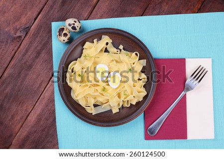 Fork and plate. Plate with egg pasta on the table. Hearty and delicious lunch on the table. Brown earthenware dish with pasta.