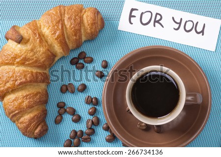 Croissant and a cup of strong black coffee. Cup of coffee and a bun. Breakfast treat. Breakfast croissant and coffee. Note \