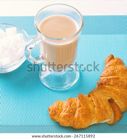 Morning coffee and croissant on the table. Pastries and coffee. Coffee with milk in a beaker with a handle. French breakfast.
