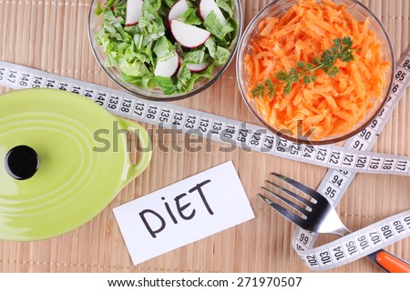 Two salads. To lose weight, weight loss, healthy food. Radish salad and greens. Grated carrots. Pan, two bowls of salad and a measuring tape on the table. Sliced vegetables.
