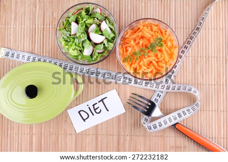 Two salads. Sliced vegetables. To lose weight, weight loss, healthy food.  Grated carrots. Pan, two bowls of salad and a measuring tape on the table. Radish salad and greens.