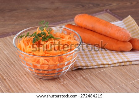Grated and whole carrots. Carrot salad in a salad bowl on the table. Carrots and greens. Healthy vegetables, carotene, vitamin A. Therapeutic diet, weight loss. Carrots for Breakfast.