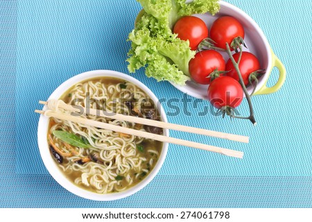 Chinese noodles in soup. Soup with noodles and mushrooms. The seafood chowder. Chinese chopsticks. Kitchen Asia. The vegetables on the plate. Tomatoes on the branch and lettuce. Dinner on the table.