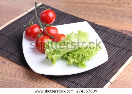 Vegetables on a square plate. Organic vegetables. The cherry tomatoes on a branch. Red tomatoes on a branch, lettuce. Diet food. Dieting, weight lose. Delicious and healthy lunch. The veggie platter.