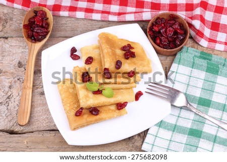 Pancakes with cranberries and mint. Delicious sweet pancakes. Fork, a plate with pancakes, spoon and dried fruits. Table, tablecloth, plate and Cutlery. Good morning. Breakfast. Top view. Lunch time.